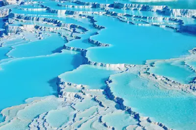 Close view of turquoise thermal pools separated by white mineral travertine terraces at Pamukkale, Turkey.