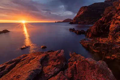 Sunrise over red granite rocks and the rugged coastline at Sleepy Bay in Freycinet National Park, Tasmania.