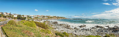 Rocky Atlantic coastline at Yzerfontein with coastal vegetation, ocean waves and homes overlooking the shoreline on South Africa's West Coast.
