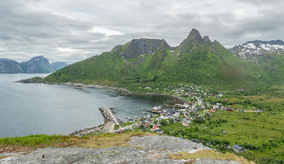 Elevated view of Mefjordvær village on Senja with fjord coastline, breakwater, and steep green mountains in northern Norway