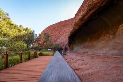 Boardwalk beside a large rock shelter at the base of Uluru in Uluru-Kata Tjuta National Park, Australia.