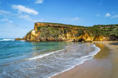 Sandy beach, turquoise water and rugged limestone cliffs at Childers Cove in Victoria, Australia.