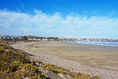Wide sandy beach at Paternoster with whitewashed houses along the shoreline, viewed at low tide on South Africa’s West Coast beneath a blue sky.