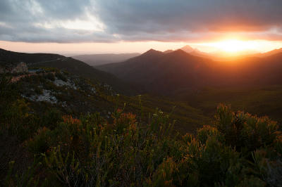 Sunset view from Robinson Pass with layered mountain ridges, fynbos vegetation and golden light across the Outeniqua Mountains.