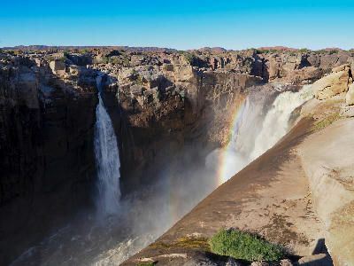Augrabies Falls cascading into a granite gorge with a rainbow forming in the spray, Northern Cape, South Africa.