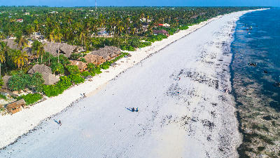 Aerial view of Matemwe Beach with white sand, beachfront lodges, palm trees, and the turquoise Indian Ocean in Zanzibar, Tanzania.
