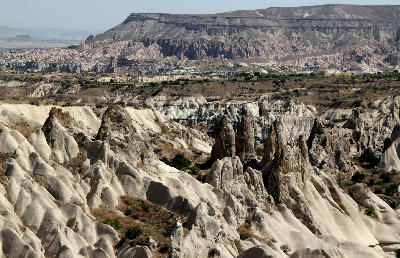 Pale eroded ridges and rock pinnacles across White Valley with layered hills in the background, Cappadocia, Turkey.