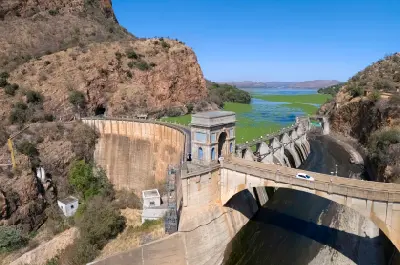 Aerial view of Hartbeespoort Dam and dam wall set between rocky Magaliesberg mountains, with the reservoir stretching into the distance in North West Province, South Africa.
