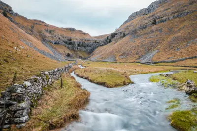 Cascading waterfalls flowing over limestone boulders between steep rock walls inside Gordale Scar, North Yorkshire.