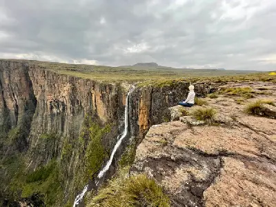 Hiker at the edge of the Amphitheatre viewing Tugela Falls cascading over the escarpment in Royal Natal National Park, Drakensberg, South Africa.