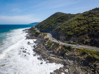 Aerial view from the Teddy’s Lookout area showing the Great Ocean Road winding between forested hills and the rugged coastline near Lorne, Victoria.
