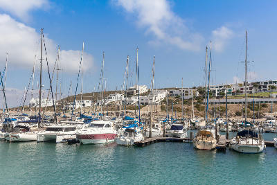 Sailing yachts and motorboats moored in the marina at Club Mykonos, with whitewashed resort buildings overlooking the harbour in Langebaan, South Africa.
