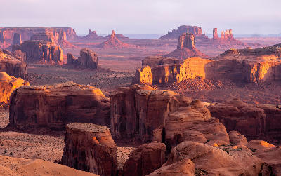 Monument Valley red rock formations glowing in golden light with multiple buttes and mesas across desert landscape