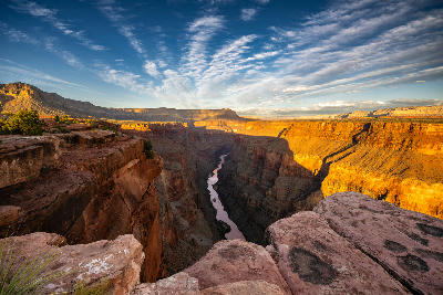 Sunrise at Toroweap Lookout on the North Rim of the Grand Canyon, with golden light illuminating sheer canyon walls and the Colorado River far below.