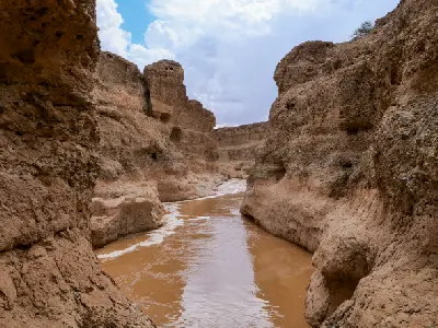 Mud-brown floodwater moving through steep sandstone walls inside Sesriem Canyon near Sossusvlei, Namibia.