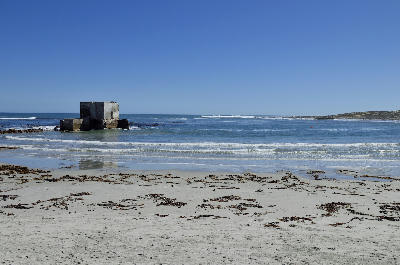 Historic copper export loading ruins standing offshore at Hondeklip Bay, with a sandy beach and Atlantic Ocean coastline in the Northern Cape, South Africa.