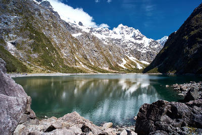 Lake Marian surrounded by steep alpine cliffs and snow-covered peaks in Fiordland National Park, South Island, New Zealand.