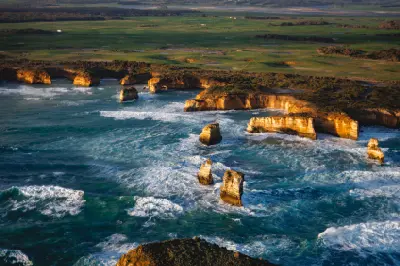 Aerial view of limestone cliffs, offshore sea stacks, rough Southern Ocean and green farmland along Victoria’s Shipwreck Coast.