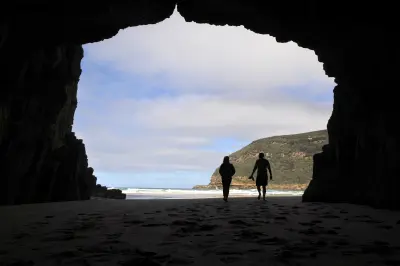 Silhouetted visitors inside Remarkable Cave looking towards the ocean on the Tasman Peninsula, Tasmania.