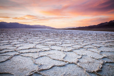 Badwater Basin salt flats at sunset in Death Valley National Park California with polygon salt patterns and distant desert mountains
