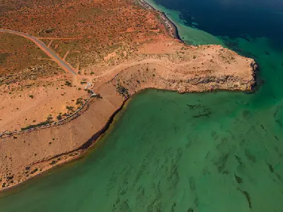 Aerial view of Eagle Bluff with its boardwalk, ochre cliffs and clear green waters along the Shark Bay coast.