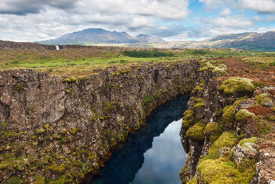 Rocky tectonic fissure filled with clear water at Þingvellir National Park in Iceland.