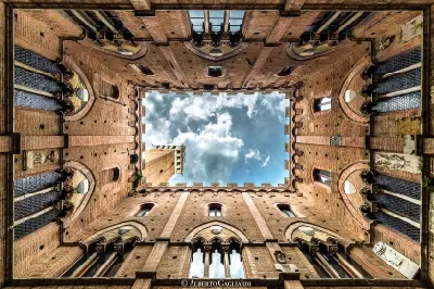 Looking up from the courtyard of Palazzo Pubblico toward the Torre del Mangia in Siena, Tuscany, Italy.
