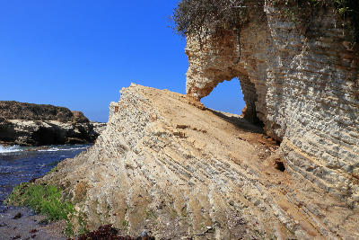 Natural sandstone arch formation along the rocky coastline of Montaña de Oro State Park, California.