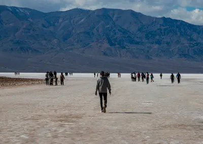 People walking on Badwater Basin salt flats in Death Valley National Park California with mountains in background