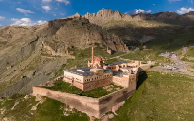 Aerial view of İshak Pasha Palace and its fortified walls beneath rugged mountains near Doğubayazıt, Turkey.