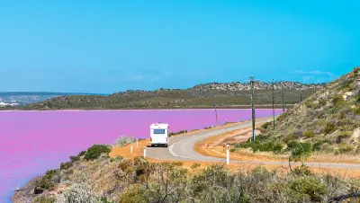 Campervan follows the coastal road beside the vivid pink waters of Hutt Lagoon near Port Gregory.