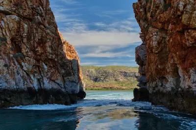 Powerful tidal water surges through a narrow rock gap at Horizontal Falls, framed by towering cliffs of the McLarty Range.