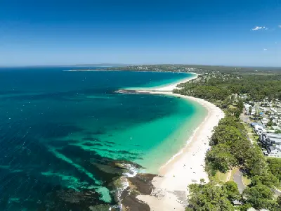 Sweeping aerial view across Jervis Bay with turquoise water, white-sand beaches and the coastal communities of Huskisson and Vincentia.