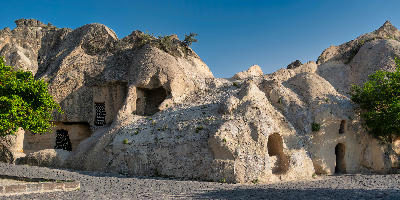 The rock-cut Chapel of St. Basil at Göreme Open Air Museum in Cappadocia, Turkey, with cave chambers and ancient stone architecture beneath a clear blue sky.