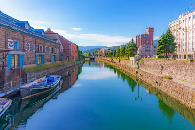 Historic warehouse buildings and calm water reflections along Otaru Canal in summer, Hokkaido, Japan.