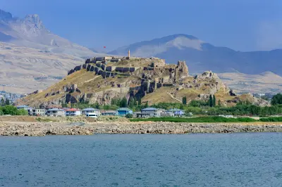 Van Castle on a rocky ridge overlooking the blue waters of Lake Van with mountains in the background.