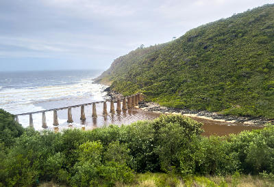 Kaaimans Railway Bridge crossing the Kaaimans River estuary beneath forested coastal cliffs along the Garden Route near Wilderness, South Africa.