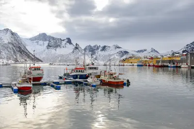 Winter harbour scene in Husøy showing moored fishing boats and snowy mountain backdrop across the fjord
