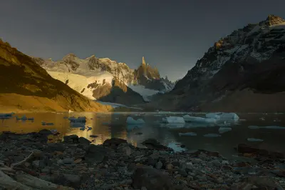 Sunrise at Laguna Torre with golden light on Cerro Torre and icebergs floating in the lake, Patagonia, Argentina.