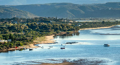 Boats anchored on the Keurbooms Estuary with sandy shorelines and mountain ridges near Plettenberg Bay.