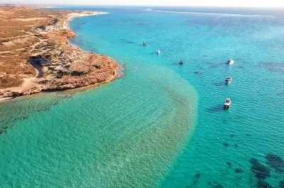 Aerial view of boats over clear turquoise water and shallow reef off Coral Bay.