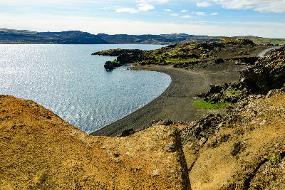 Black sand shoreline and calm water at Kleifarvatn lake on the Reykjanes Peninsula, Iceland.