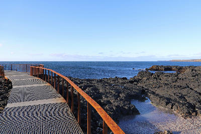 Metal viewing platform overlooking Brimketill lava pool on the volcanic coast of the Reykjanes Peninsula, Iceland.