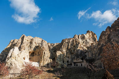 Rock-cut churches and cave dwellings at the Göreme Open Air Museum in Cappadocia, Turkey, carved into towering volcanic cliffs beneath a clear blue sky.