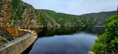 Kouga Dam and reservoir surrounded by steep mountain slopes in the Baviaanskloof region of the Eastern Cape, South Africa, with calm water reflecting the rugged wilderness landscape.
