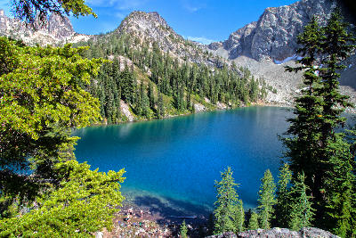 Turquoise alpine lake surrounded by forest and rocky peaks at Blue Lake in North Cascades National Park
