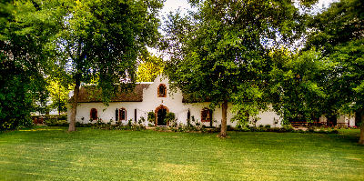 Rust en Vrede Restaurant building framed by large oak trees and lawns at Rust en Vrede Estate in Stellenbosch, South Africa.
