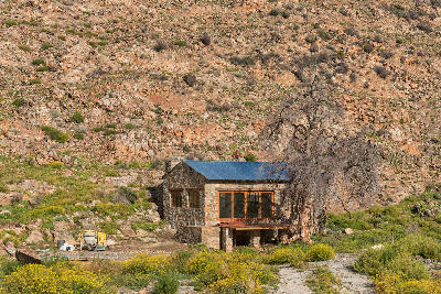 Stone cottage at Keurbosfontein near Wupperthal, surrounded by rocky mountain slopes and fynbos vegetation in the remote northern Cederberg.