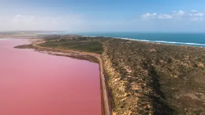 Aerial view of pink Hutt Lagoon beside the coastal road and blue Indian Ocean near Port Gregory.