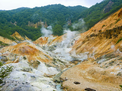 Steaming geothermal landscape with sulphur-stained slopes at Jigokudani Hell Valley in Noboribetsu, Hokkaido, Japan.
